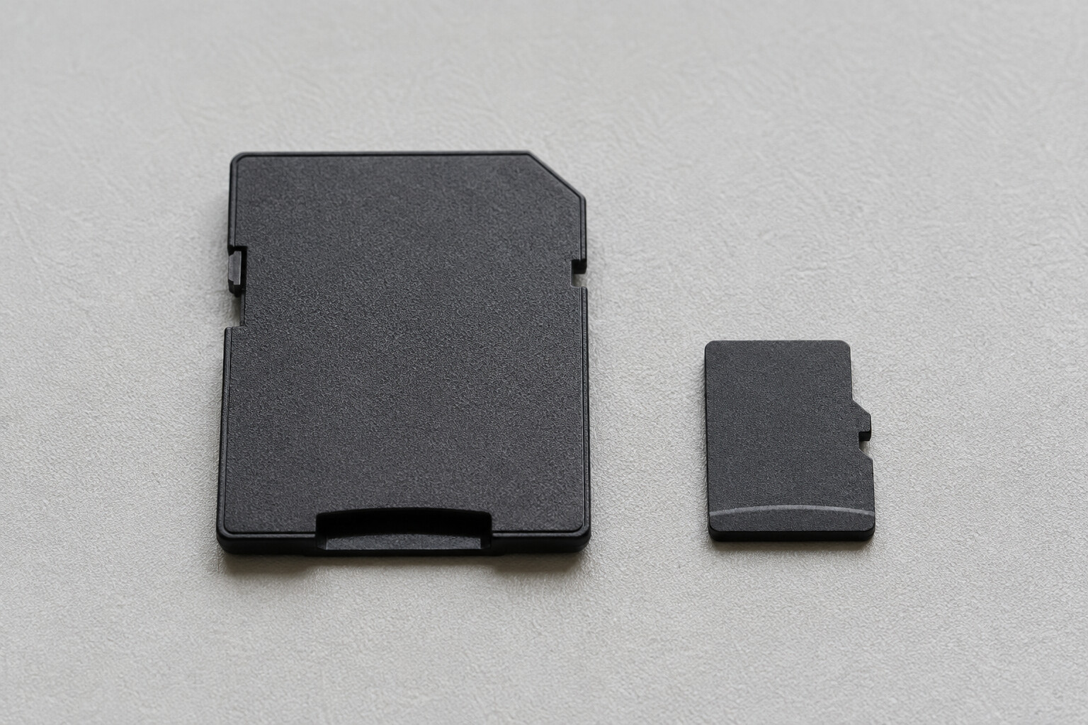 Duży adapter SD i osobna mała karta microSD na jasnym podłożu